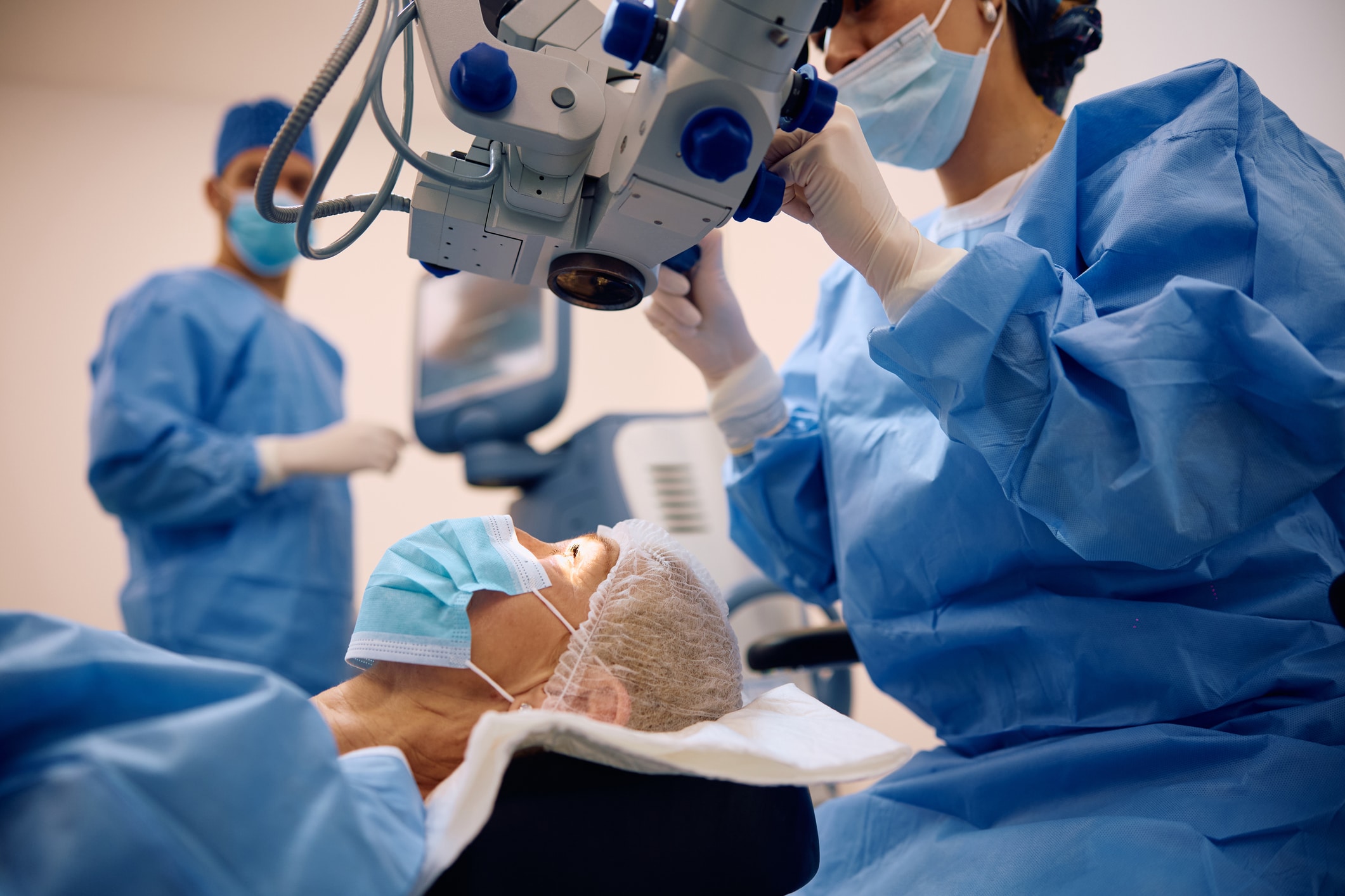 Patient lying under a surgical microscope while an ophthalmologist performs LASIK.