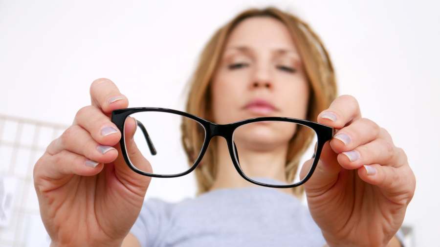 Close-up of black-framed glasses in the hands of a young woman stock photo